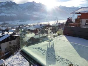 a shadow of a person on a balcony with snow covered mountains at Glas House - Design Holiday Home in Piesendorf