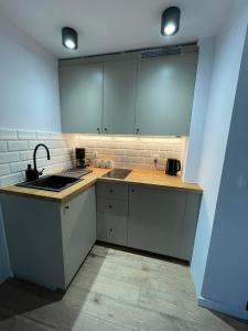 uma cozinha com armários brancos, um lavatório e um fogão em Sosnowy Apartament em Polanica-Zdrój