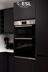een zwarte oven in een keuken met zwarte kasten bij Comfy Modern 2 Bedroom Duplex Apartment with Sun Terrace in Shrewsbury