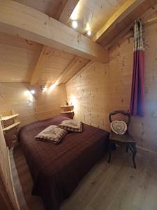 ein Schlafzimmer in einem Blockhaus mit einem Bett und einem Stuhl in der Unterkunft Le Flocon des Aravis in La Giettaz