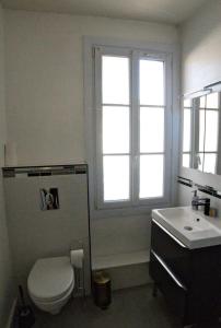 een badkamer met een toilet, een wastafel en een raam bij Chez Pia in Dieppe