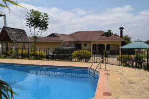 a house with a swimming pool in front of a fence at Stasumo House Arusha in Arusha
