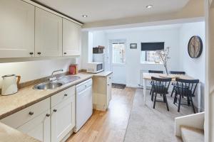 eine Küche mit weißen Schränken und einem Tisch und Stühlen in der Unterkunft Host & Stay - Waterlily Cottage in Great Ayton + 13 Fotos