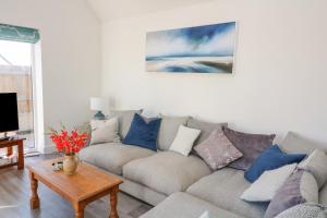 a living room with a gray couch with blue pillows at Driftwood, 29 Furzedown Road in Kingsbridge