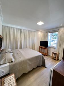 een slaapkamer met een bed en een flatscreen-tv bij Pousada Tiradentes in Tiradentes