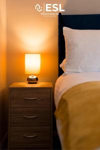 een bed met een nachtkastje met een lamp erop bij Comfy Modern 2 Bedroom Duplex Apartment with Sun Terrace in Shrewsbury