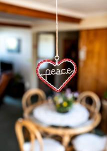 Ein Herzzeichen, das sagt, Frieden hängt über einem Tisch in der Unterkunft Zoete Inval in Hermanus