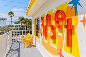 a mural on the side of a building with yellow chairs at Sunset Inn and Cabanas in St. Pete Beach