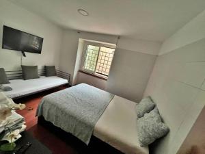 a bedroom with a bed and a couch and a window at Room in Queluz 11 minutes from Lisbon in Queluz