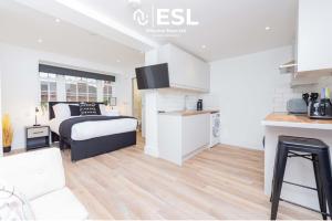 a white bedroom with a bed and a kitchen at Studio 3, Top Floor Town Centre Apartment in Shrewsbury