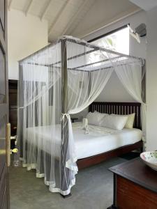 a bedroom with a canopy bed with white drapes at Wasantha Garden Hotel Restaurant & Ayurvedic Treatment in Weligama
