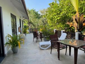a patio with chairs and tables and trees at Wasantha Garden Hotel Restaurant & Ayurvedic Treatment in Weligama