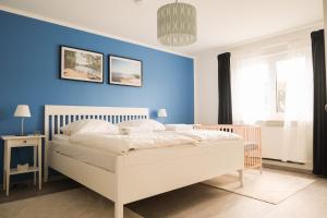 een slaapkamer met een wit bed en een blauwe muur bij Haus Hummel in Lieske