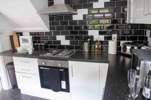 a kitchen with a black and white tile wall at Afan Valley Home - Contractor Accommodation in Port Talbot +19 photos