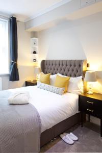 1 dormitorio con 1 cama grande con almohadas amarillas en Avari Apartments - Winchester Collection en Londres