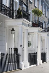 una casa blanca con columnas blancas y una valla en Avari Apartments - Winchester Collection en Londres