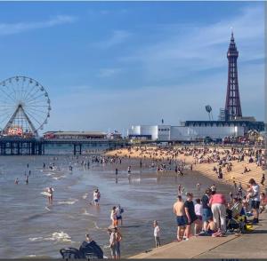 a crowd of people on a beach near a pier at Cheerful 2-bedroom home with off street parking in Blackpool
