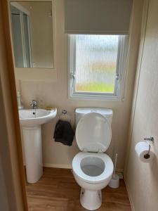 a bathroom with a toilet and a sink and a window at Coyles retreat in Stranraer