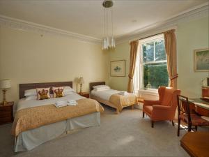 a bedroom with two beds and a desk and a window at Clonyard House Hotel in Dalbeattie