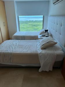1 dormitorio con 2 camas y ventana grande en Luxury Apartment in Ocean Pavillion Hotel, en Cartagena de Indias