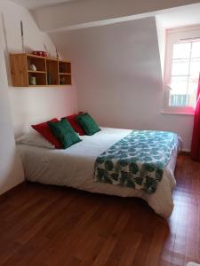 een slaapkamer met een bed met groene en rode kussens bij La P'tite Normande in Villerville
