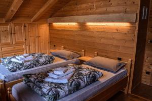 2 łóżka w pokoju z drewnianymi ścianami w obiekcie Appartamento Mainardi w mieście Auronzo di Cadore
