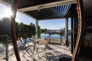 a screened porch with chairs and a table on the water at La Mare Boathouse, Tallinn in Tallinn