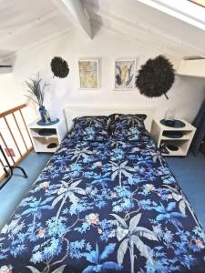 1 dormitorio con 1 cama con colcha de flores azul en Coquet studio meublé avec jardin, en Mauguio