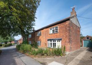 an old brick house with white windows on a street at 6 North Green in Southwold