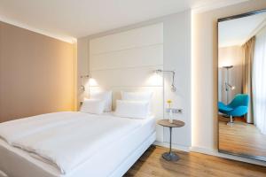1 dormitorio con 1 cama blanca y 1 silla azul en NH Berlin Alexanderplatz en Berlín