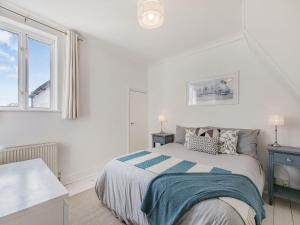 a white bedroom with a bed and a window at Kiwi Cottage in Whitstable
