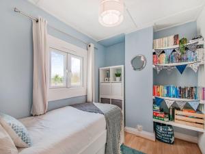 a bedroom with blue walls and a bed with a window at Kiwi Cottage in Whitstable