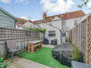 a backyard with a wooden fence and a wooden table at Kiwi Cottage in Whitstable