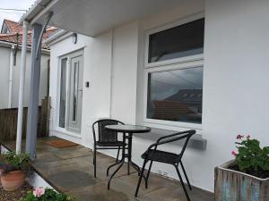 een patio met 2 stoelen en een tafel naast een raam bij Contemporary one bed studio. Sea views and parking in Westward Ho