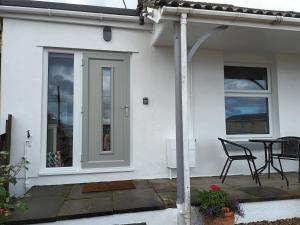 a white house with a patio with a table and chairs at Contemporary one bed studio. Sea views and parking in Westward Ho