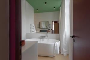 Baño blanco con bañera y espejo en MiHotel Blandan en Lyon