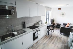 a kitchen with white cabinets and a living room at Central Studio - New - FREE Wi-Fi - City Centre in Sheffield