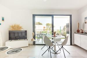 a living room with a table and chairs and a television at Superbe Appartement T2 avec Piscine et Vue Mer in Fréjus