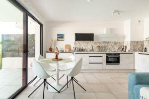 a white kitchen with a white table and chairs at Superbe Appartement T2 avec Piscine et Vue Mer in Fréjus