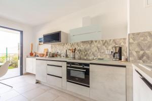 a white kitchen with a stove and a sink at Superbe Appartement T2 avec Piscine et Vue Mer in Fréjus