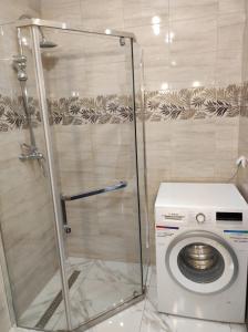 a bathroom with a shower and a washing machine at Apartament Parkowa in Olecko