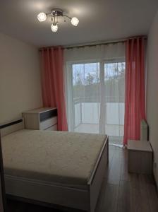 a bedroom with a bed and a large window at Apartament Parkowa in Olecko