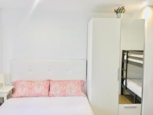 a small bedroom with a white bed and a mirror at APARTAMENTO Luis in Suances