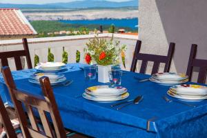 a blue table with plates and flowers on a balcony at Apartments Loncar in Jadranovo