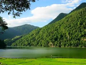 a large green lake with mountains in the background at Pac Ngoi Village Homestay in Ba Be +67 photos