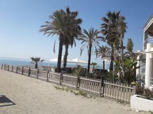 uma cerca ao lado de uma praia com palmeiras em Appartamento vittoria em Pietra Ligure