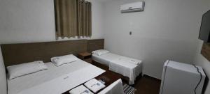 um pequeno quarto com 2 camas e uma janela em Astro Hotel em Rondonópolis