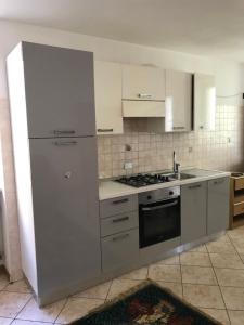 una cocina con electrodomésticos de acero inoxidable y armarios blancos en Casa Stablum, en Malè