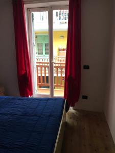 1 dormitorio con 1 cama y una ventana con cortinas rojas en Casa Stablum, en Malè