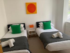 2 bedden met groene en witte kussens in een kamer bij The Apartment Boscawen Woods in Truro